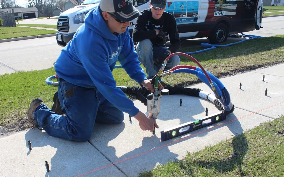 Foam-Tek crew checking a sidewalk lift against a level during polyurethane injection