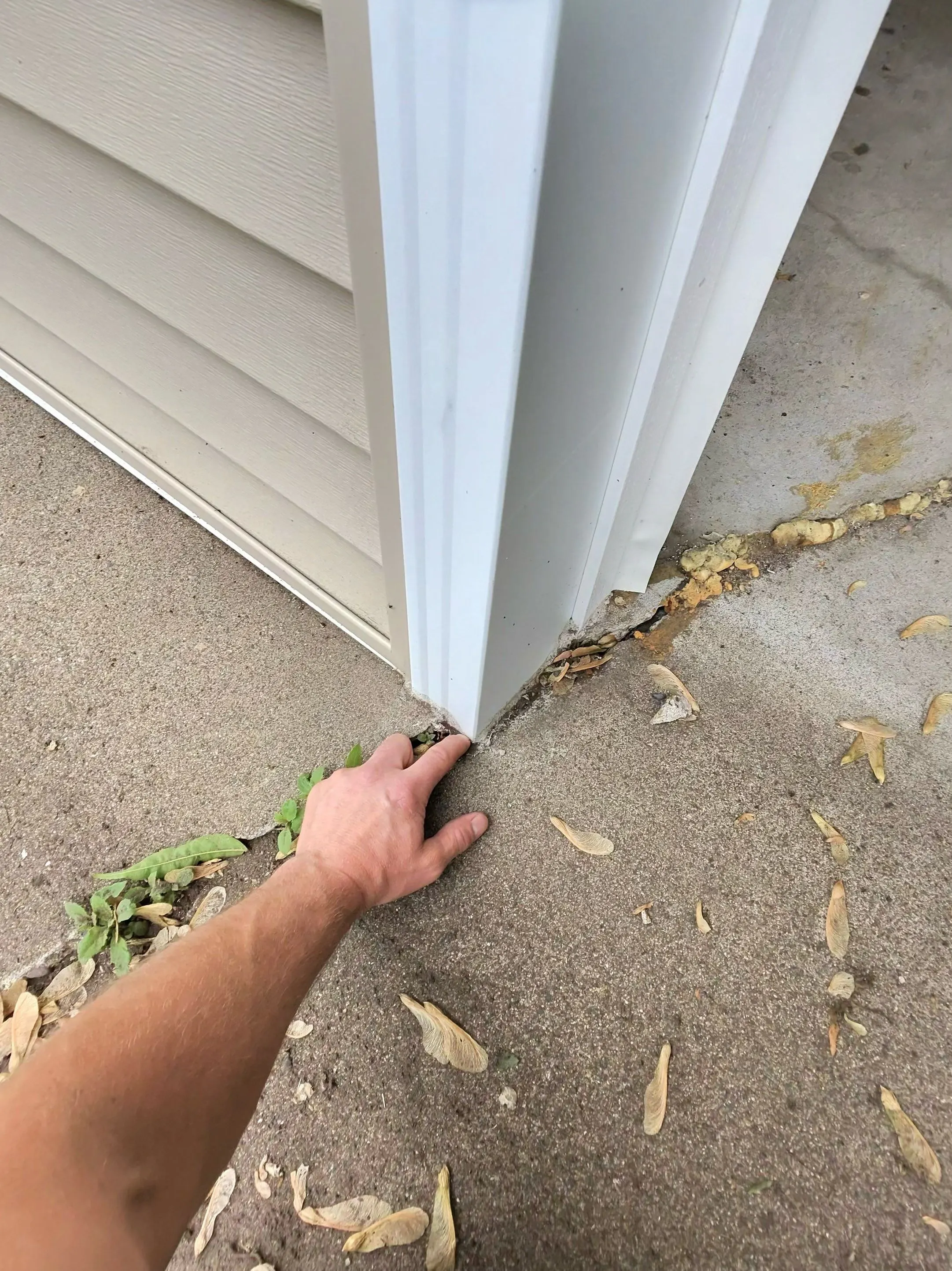 Separated seam where a concrete slab pulled away from the side of a house