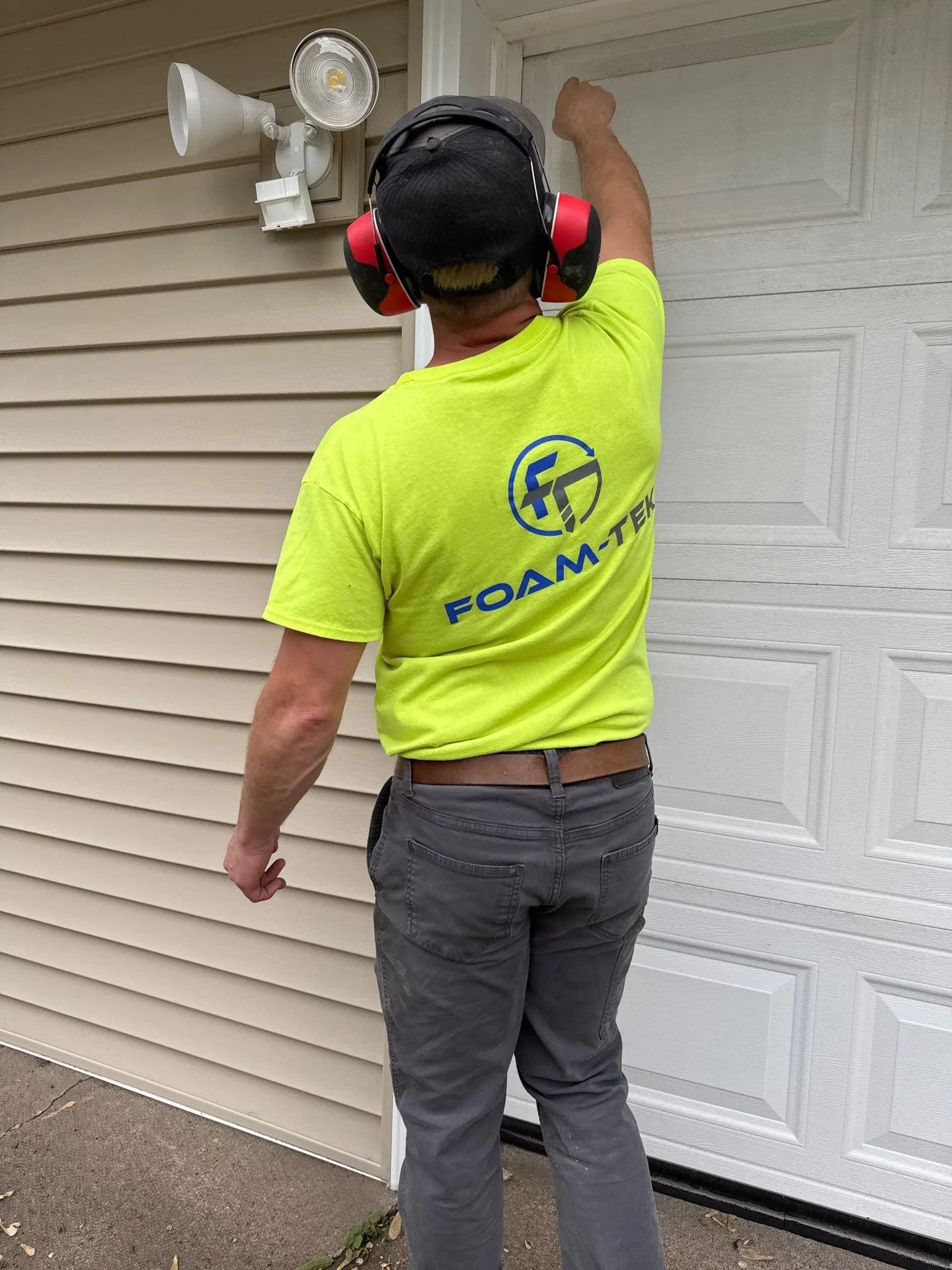 Foam-Tek technician in a branded shirt working at a garage door opening