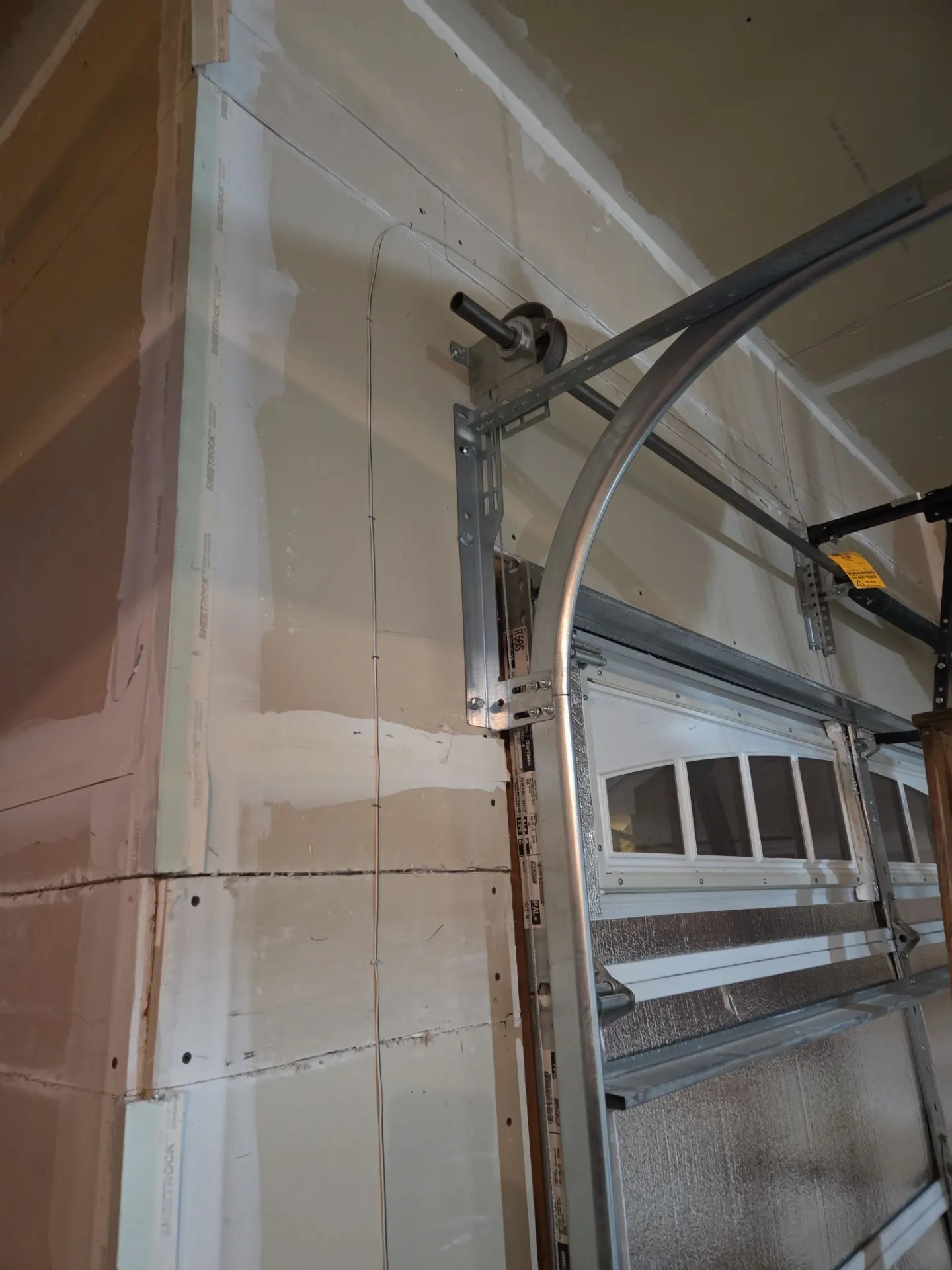 Spray foam sealing the header and wall above a garage door opening