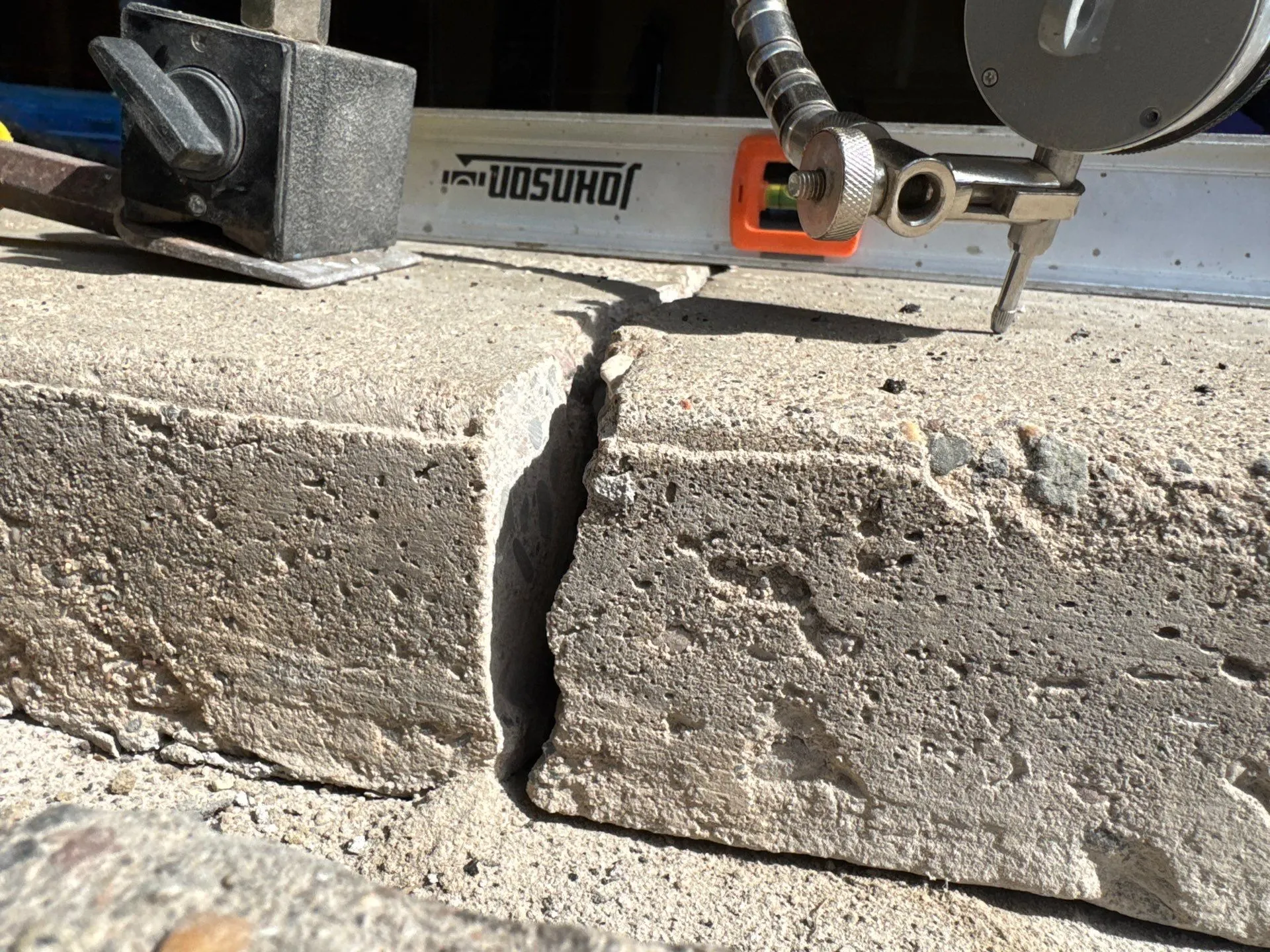 A level laid across a settled concrete slab showing how far the section dropped